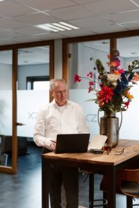man staat aan hoge tafel met laptop en kijkt naar de zij