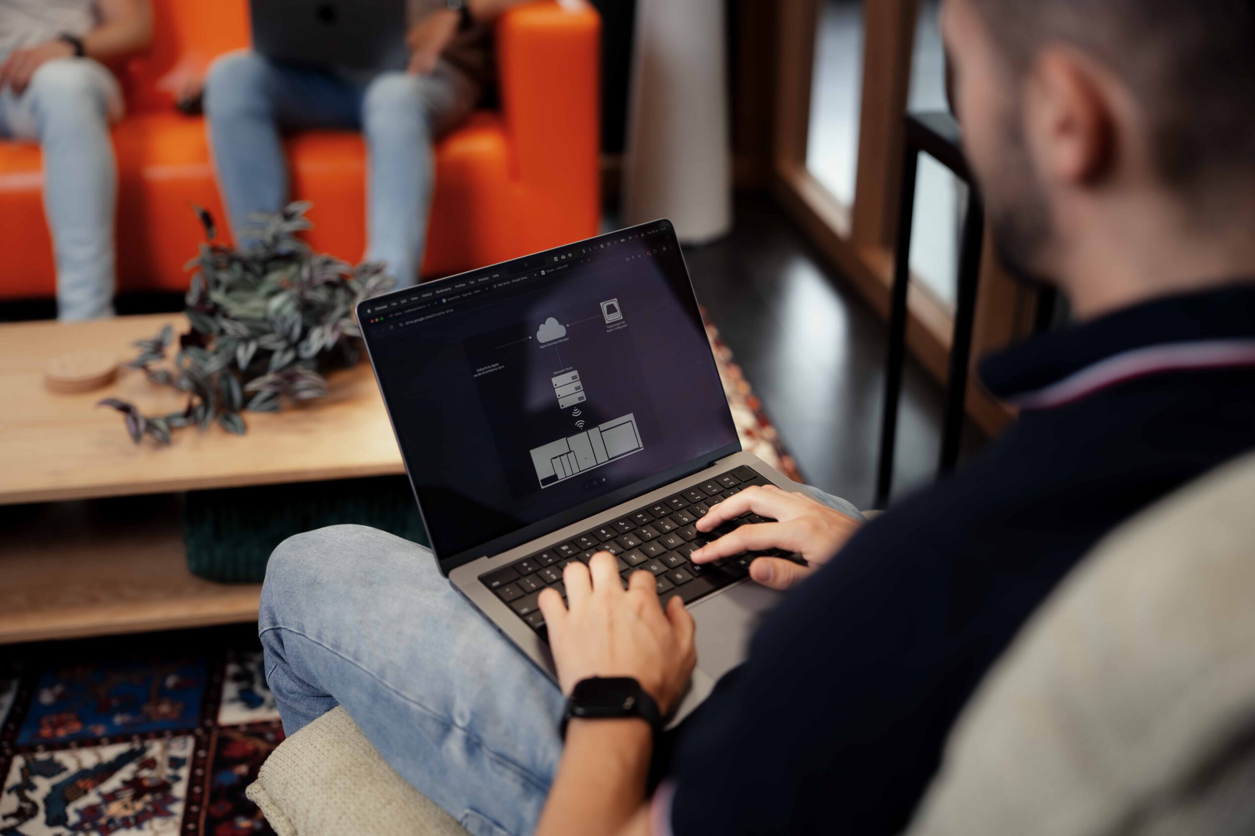 Beeld van achteren, met een medewerker die aan het typen is op een laptop, gezien over zijn schouder